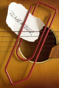 Torn note with the words "Remember" paperclipped to guitar strings